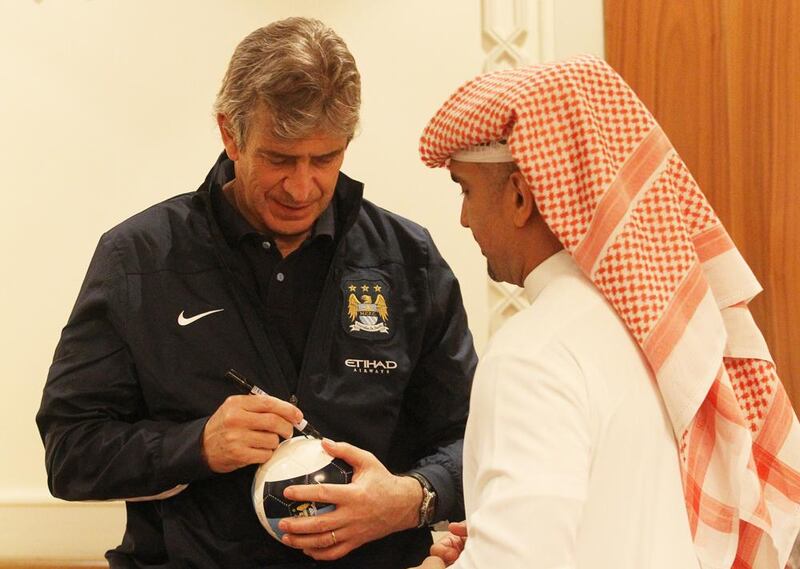 The Manchester City manager Manuel Pellegrini signs autographs for fans and the people of Etihad at the airport on arrival in Abu Dhabi. Courtesy EAA 