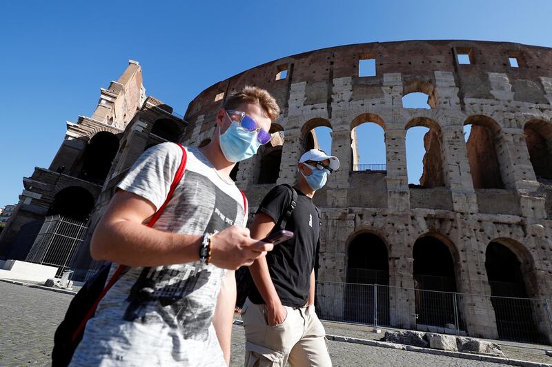 People wearing face masks walk past the Colosseum in Rome, Italy. Reuters