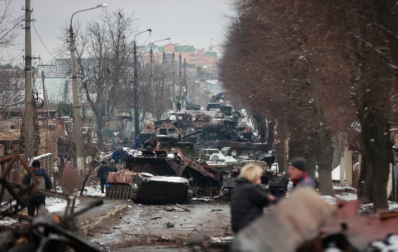 People look at the gutted remains of Russian military vehicles on a road in the town of Bucha. AP