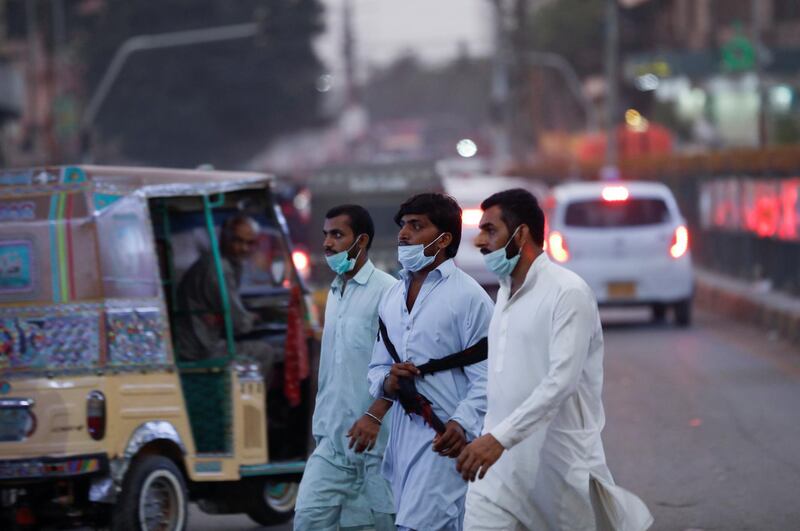Men wearing protective masks cross a road after Pakistan lifted lockdown restrictions, as the coronavirus disease (COVID-19) outbreak continues, in Karachi, Pakistan August 18, 2020. REUTERS/Akhtar Soomro