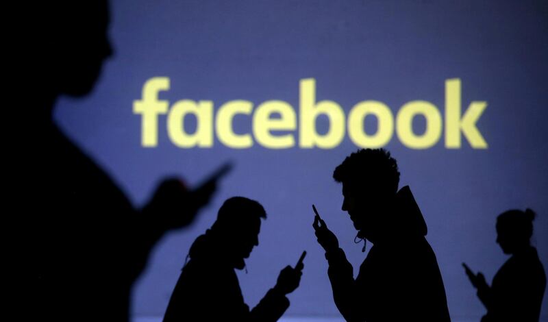 FILE PHOTO: Silhouettes of mobile users are seen next to a screen projection of Facebook logo in this picture illustration taken March 28, 2018.  REUTERS/Dado Ruvic/File Photo