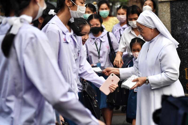 A nun gives protective facemasks to students outside a Catholic school in Bangkok.  AFP