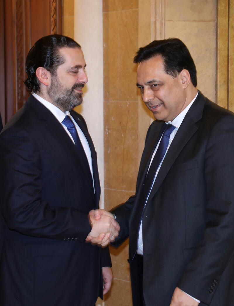 In this photo released by Lebanon's official government photographer Dalati Nohra, Lebanese Prime Minister-designate Hassan Diab, right, shakes hands with outgoing Prime Minister Saad Hariri, left, in Beirut, Lebanon. AP