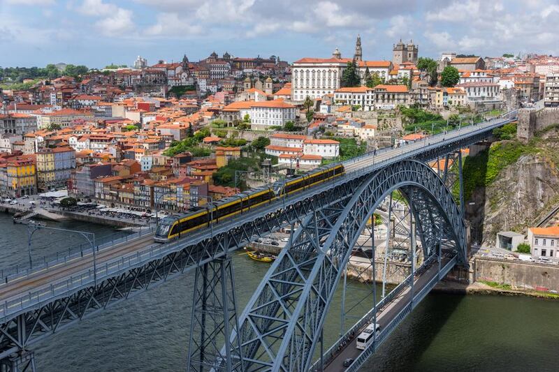 Tram crossing the Dom Luis I Bridge over the Douro River, with the historic city centre of Porto visible in the background. Getty Images