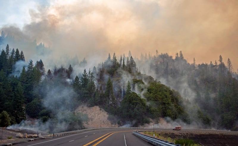 TOPSHOT - A fire truck drives along Highway 299 as they Carr fire continues to burn near Whiskeytown, California on July 28, 2018.  The US federal government approved aid on July 28 for California as thousands of firefighters battled to contain a series of deadly raging wildfires that have killed six people, including two young children and their great grandmother, and destroyed hundreds of buildings. / AFP / JOSH EDELSON
