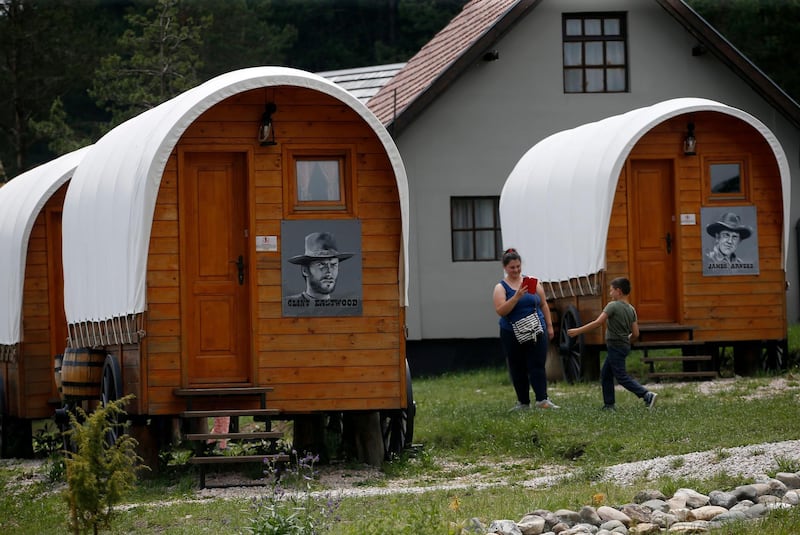 In this photo taken on June 25, 2020, visitors walk by wagons adorned with portraits of famous Western movie actors at El Paso City theme park in village of Vodice, on the Zlatibor mountain, Serbia. Darko Vojinovic / AP