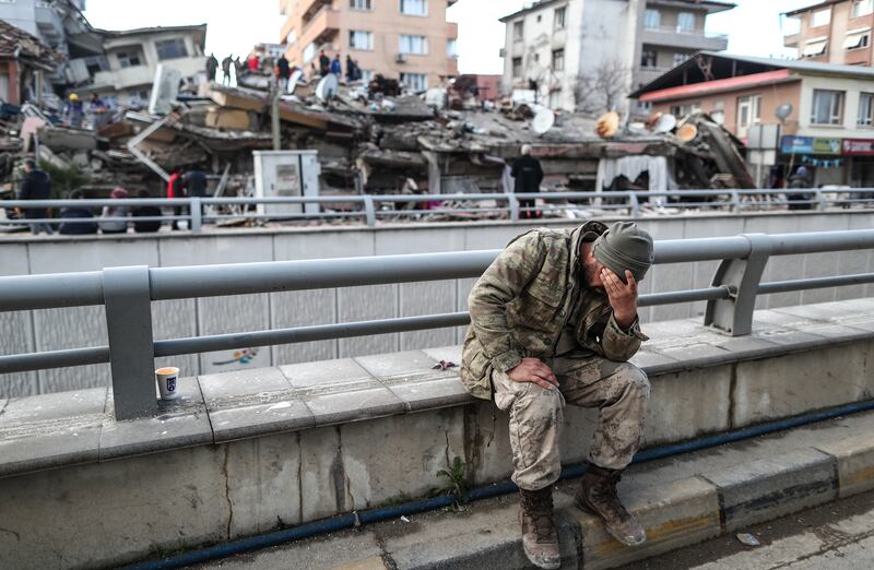 A Turkish soldier in front of a collapsed building in Hatay. EPA