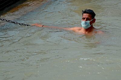 In this picture taken on June 11, 2020, a Hindu devotee wearing a facemask takes a dip at Har Ki Pauri Ghat on the banks of the river Ganges, after the government eased a nationwide lockdown imposed as a preventive measure against the COVID-19 coronavirus at Haridwar in Uttarakhand state. Life is slowly returning to normal among the hallowed temples of Haridwar, one of Hinduism's holiest places, but the Indian pilgrimage town still has a forlorn air as the country emerges from its coronavirus lockdown. - TO GO WITH Virus-health-India-religion-tradition-tourism,SCENE by Bhuvan BAGGA
 / AFP / Money SHARMA / TO GO WITH Virus-health-India-religion-tradition-tourism,SCENE by Bhuvan BAGGA
