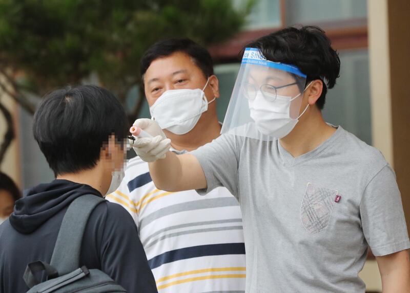 A person checks a young applicant's body temperature at a middle school in South Korea's southwestern city of Gwangju.  EPA