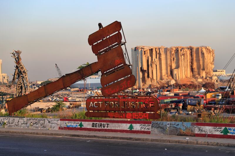 A monument representing justice in front of grain silos gutted in the August 2020 explosion at the port that killed more than 200 people and injured more than 6,000, in Beirut, Lebanon.  AP