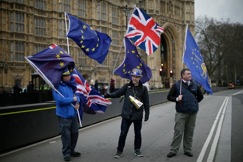 Demonstrators opposing Brexit wave flags as The European Commission's Chief Negotiator for the UK exiting the European Union, Michel Barnier is at 10 Downing Street for a meeting, outside the Houses of Parliament, London, Monday, Feb. 5, 2018. (AP Photo/Tim Ireland)