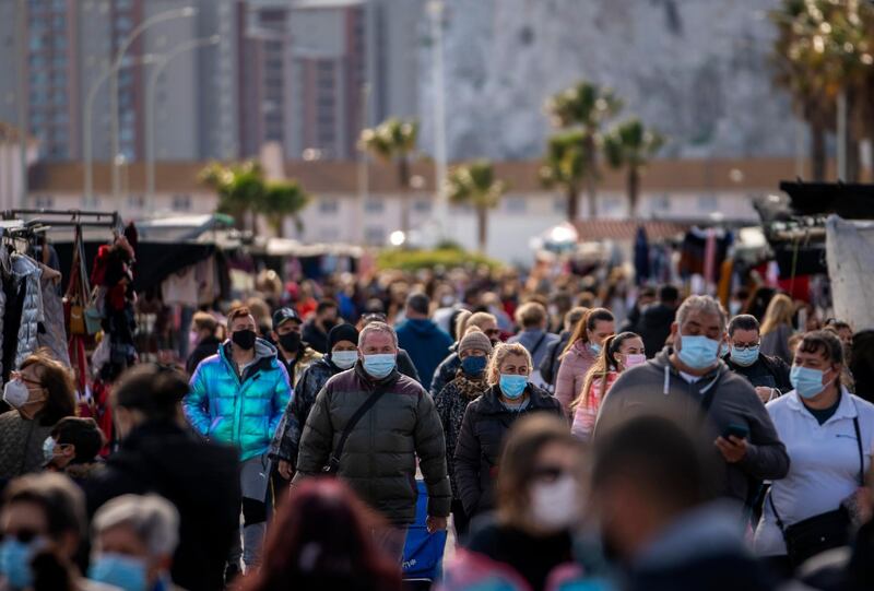 Backdropped by the Gibraltar rock, people wearing face masks walk along the stalls of a weekly market at the Spanish city of La Linea. AP Photo