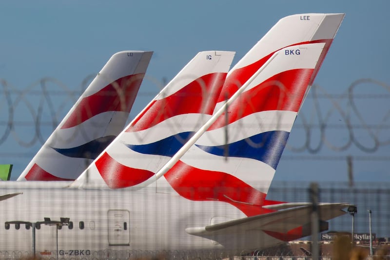 British Airways livery sits on the tail fins of passenger aircraft operated by British Airways, a unit of International Consolidated Airlines Group SA (IAG), sitting on the tarmac at London Heathrow Airport, London, U.K. on Monday, March 16, 2020. Airlines worldwide will shrink operations to only a trickle of flights, severing global links and putting hundreds of thousands of jobs at risk as they fight to preserve cash and survive the coronavirus pandemic. Photographer: Jason Alden/Bloomberg
