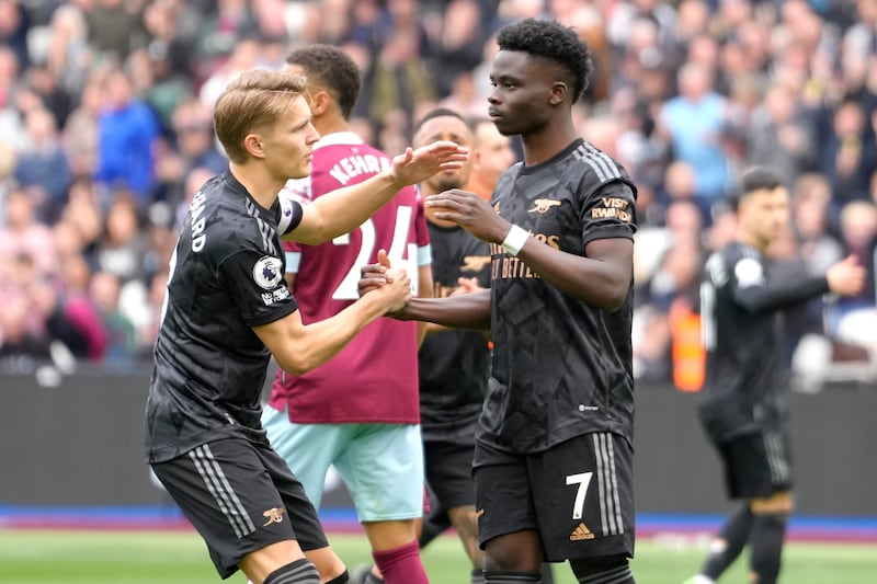 Arsenal's Martin Odegaard, left, puts his arm around Arsenal's Bukayo Saka after Sako failed to score from a penalty kick during the English Premier League soccer match between West Ham United and Arsenal at the London stadium in London, Sunday, April 16, 2023.  (AP Photo / Kirsty Wigglesworth)