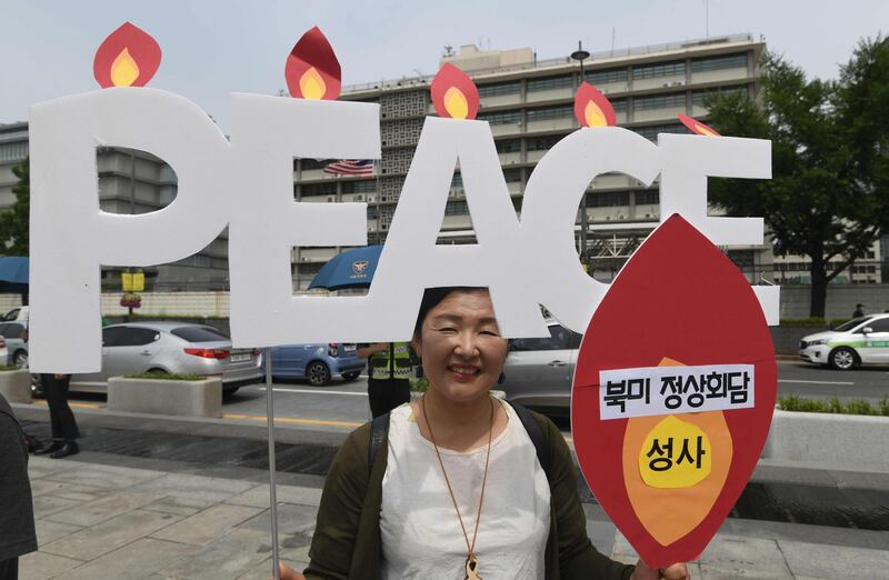 A protester holds a sign reading "Peace" during an anti-Trump rally near the US embassy in Seoul on May 25, 2018. South Korea's Unification Minister said on May 25 that Seoul will press ahead with improving ties with North Korea after US President Donald Trump abruptly cancelled a summit with Pyongyang's leader Kim Jong Un. / AFP / Jung Yeon-je
