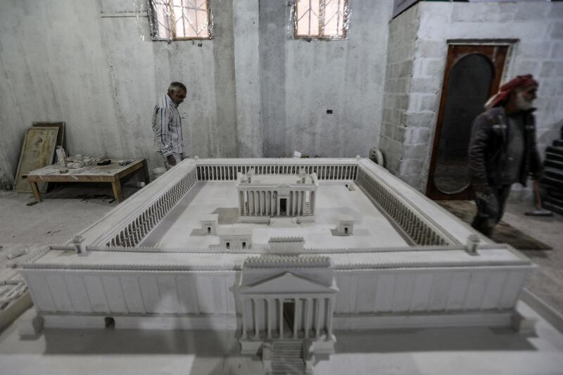 Ali Saleh (L), a 58-year-old displaced Syrian originally from Palmyra, builds from memory a wood and gypsum model of a prominent archaeological landmark of his home city that was heavily damaged by Islamic State (IS) militants, at a workshop home in the rebel-held city of al-Bab northwest of Aleppo in northern Syria on January 14, 2021. - Ten years of Syria's civil war have robbed Saleh of his home in the desert city, his three sons and daughter, and the last of his poor hearing, his family says. But he still vividly remembers Palmyra's ruins, where he accompanied restoration and excavation teams for 25 years, before the Islamic State group overran the city in 2015. (Photo by Bakr ALKASEM / AFP)