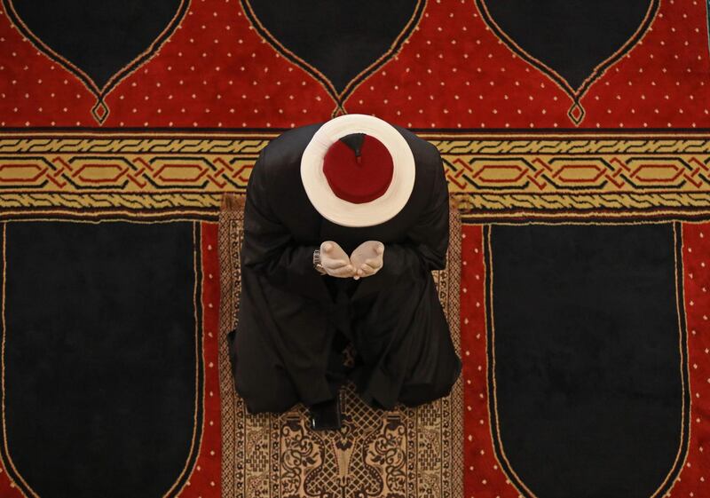 A Sunni cleric wearing protective protective gloves, prays at the Mohammed Al-Amin Mosque in Beirut.  AFP