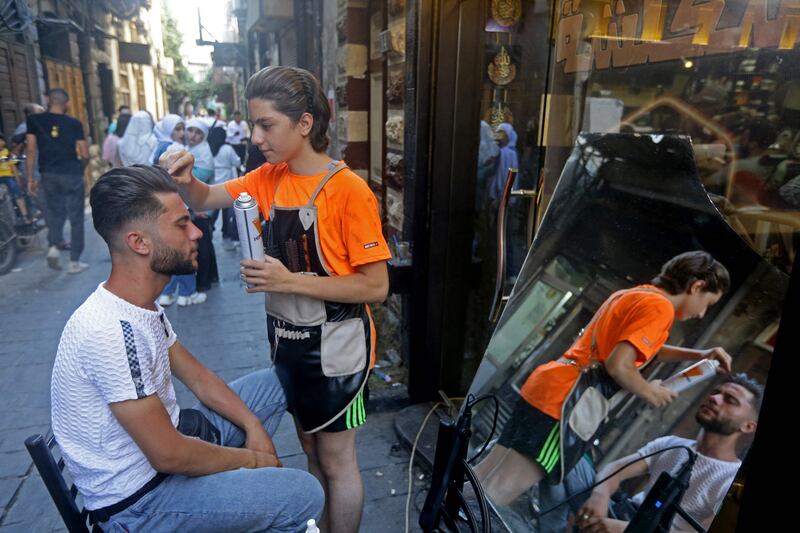 A man gets a haircut on the first day of the Eid al-Adha Muslim holiday in al-Qamariya street in old Damascus, Syria. AFP