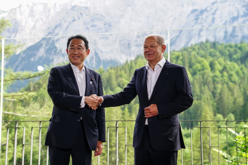 Mr Scholz shakes hands with Mr Kishida. EPA