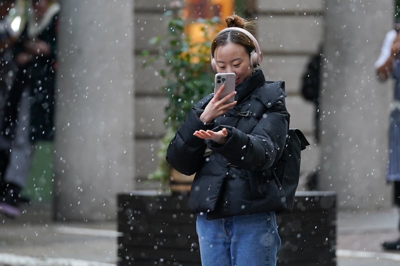 Taking photos of falling snow in Covent Garden, central London. PA