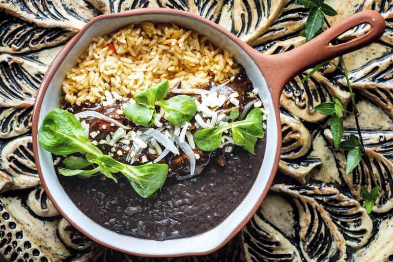 Glazed chicken with almond-based mole sauce with Mexican rice, queso fresco and refried beans at Puerto 99. Photo: Puerto 99