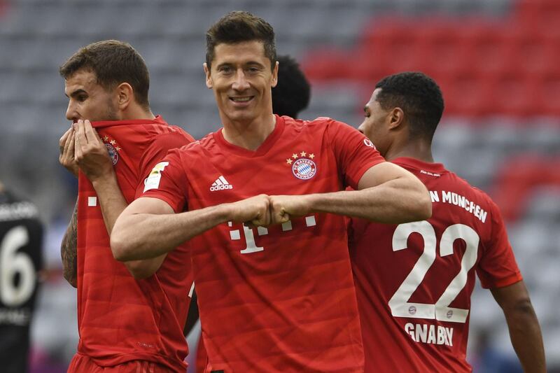 Munich players, as Robert Lewandowski, centre, celebrates scoring, taking the score to 3:0 against Fortuna D'sseldorf, during their Bundesliga soccer match played without an audience in Munich, Germany, Saturday May 30, 2020. Soccer matches are being played without an audience because of the coronavirus pandemic. (Christof Stache/Pool via AP)