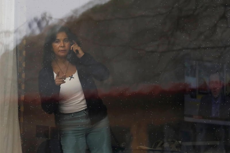 A woman who has recently arrived from Chile, looks through the window of the Radisson Blu Edwardian hotel where she is quarantined. AP Photo