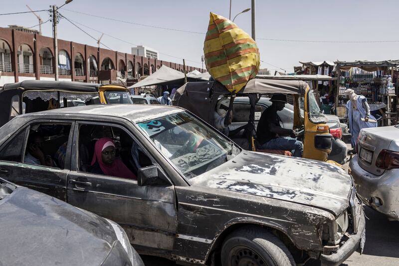A woman looks on as she sits in a taxi making his way through heavy traffic in the Marche Capital in Nouakchott, on March 11, 2023.  (Photo by MARCO LONGARI  /  AFP)