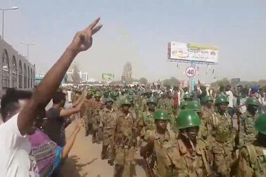 Demonstrators salute soldiers during a protest in Khartoum, Sudan April 10, 2019 in this still image taken from a video obtained from social media. Social media @THAWRAGYSD