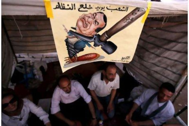 Protester sit in a makeshift tent near a poster depicting former president Hosni Mubarak in Tahrir square, Cairo. Thousands of Egyptians have packed city centres across the country since last Friday to demand faster reforms and voice frustration at what they regard as foot-dragging by military rulers and government officials. The poster reads: 'The people wants to take off the regime.' Mohamed Abd El Ghany / Reuters