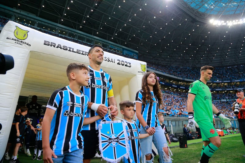 Luis Suarez heads on to the pitch with his children ahead of the match against Vasco da Gama. AFP
