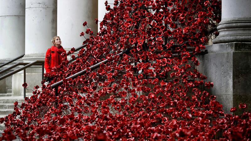 A woman looks up towards the poppy sculpture 'Weeping Window' by artist Paul Cummins and designer Tom Piper at The Imperial War Museum in London. Kirsty Wigglesworth/AP Photo