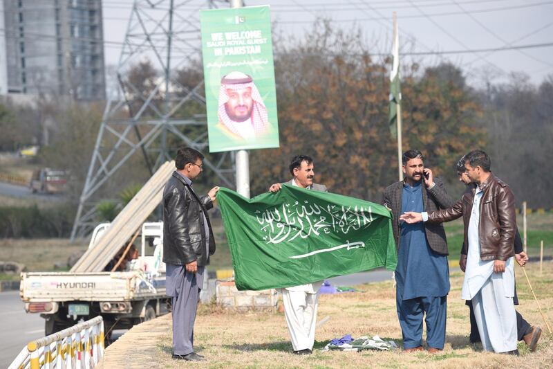 Workers hang national flags of Saudi Arabia in Islamabad. EPA