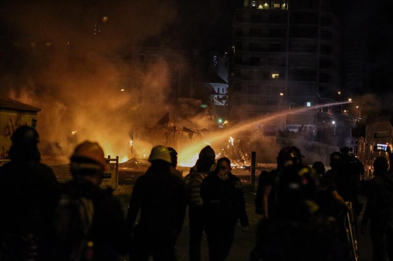 Police officers extinguish fires set in the tents of the demonstrators during clashes in central Beirut.  EPA