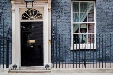 A member of staff sticks a poster of a rainbow, being used as a symbol of hope during the Covid-19 pandemic, with the words "hope" into a window at 10 Downing Street, the official residence of Britain's Prime Minister, in central London. AFP / Tolga AKMEN