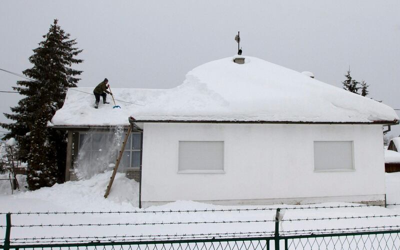 A man clears snow off the roof of a house in Sjenica, some 250 kms southwest of Belgrade, Serbia, Sunday, Feb. 5, 2012. Across Eastern Europe, thousands of people continued to dig out from heavy snow that has fallen during a cold snap that struck more than a week ago and has killed hundreds of people. (AP Photo/Samir Delic) *** Local Caption ***  Serbia Europe Weather.JPEG-0cef4.jpg