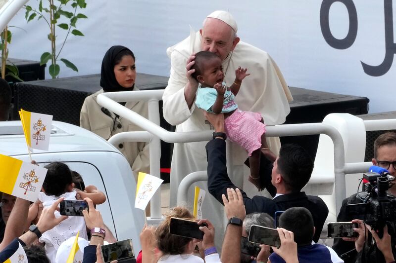 Pope Francis kisses a baby before celebrating Holy Mass at the Bahrain National Stadium on Saturday. AP