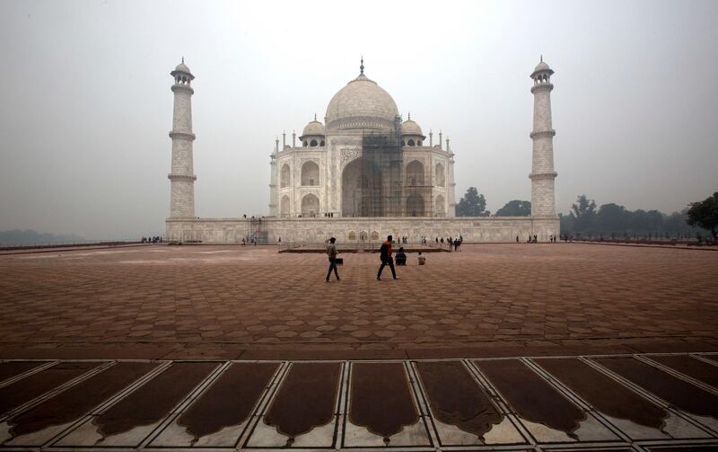 FILE - In this Dec. 5, 2017, file photo, tourists walk around Taj Mahal as workers clean the monument in Agra, India. The travel guidebook publisher Fodor's has published a list of where not to go in 2018 that includes the Taj Mahal. (AP Photo/Manish Swarup, File)