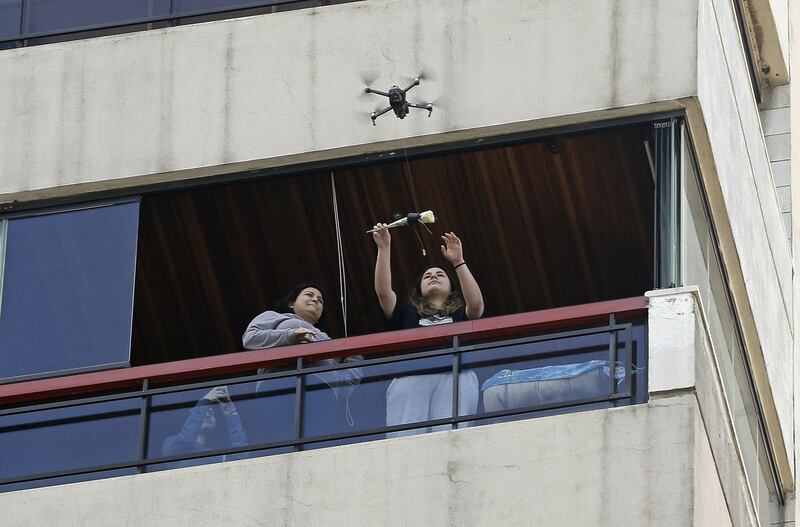 A woman on her balcony reaches out to catch a rose delivered to her via a drone on Mother's day, in the Lebanese coastal city of Jounieh, north of the capital Beirut, as people remain indoors in an effort to limit the spread of the novel coronavirus.  Three young Lebanese came up with the idea of delivering roses attached to drones, offered to mothers by their children as a surprise gift. The funds collected from this initiative will be donated to the Lebanese Red Cross to help fight against the CIVID-19 pandemic. AFP