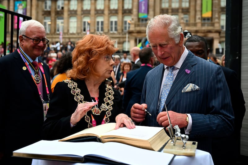 Britain's Prince Charles, standing next to the Mayor of Birmingham Maureen Cornish, signs the official book of the city's visitors during a visit to the Festival Site at Victoria Square before the opening ceremony. AP 