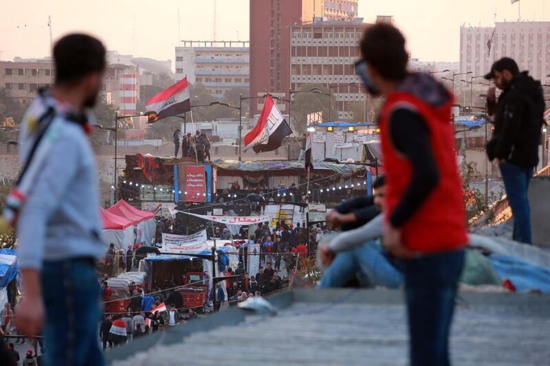 Iraqi protesters carry national flags as they gather on the Al Jumhuriya bridge, which leads to the headquarters of the Iraqi government inside the high security Green Zone area. EPA