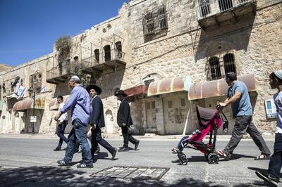 Religious Jews celebrating the Sukkoth holiday pass closed Palestinian stores in the divided area of the West Bank city of Hebron where about 900 Jewish Settlers now live on September 27,2018. (Photo by Heidi Levine for The National).