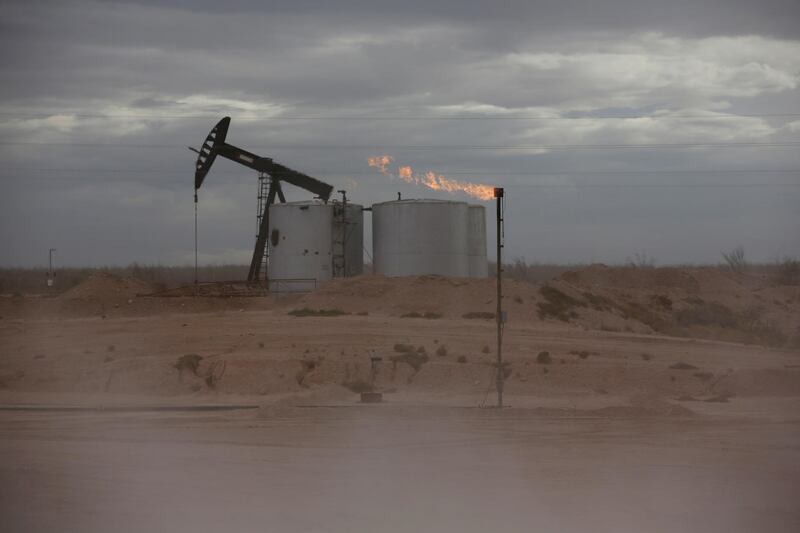 FILE PHOTO: Dust blows around a crude oil pump jack and flare burning excess gas at a drill pad in the Permian Basin in Loving County, Texas, U.S. November 25, 2019. Picture taken November 25, 2019.  REUTERS/Angus Mordant/File Photo/File Photo