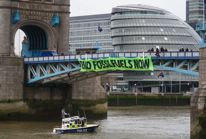 Activists hanging from the bridge by suspension cords unfurled a banner that reads: 'End fossil fuels now'. PA