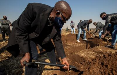 FILE - In this July 23, 2020 file photo, mourners fill the grave of health care worker Duduzile Margaret Mbonane who died from COVID-19, in Thokoza, near Johannesburg, South Africa. A South African funeral is usually an elaborate affair, often held on a Saturday, with family members and other mourners traveling from around the country, holding overnight vigils and washing the body. These days COVID-19 burials have to be held within four days, in the absence of relatives and friends and mourners being limited to fifty. (AP Photo/Themba Hadebe, File)