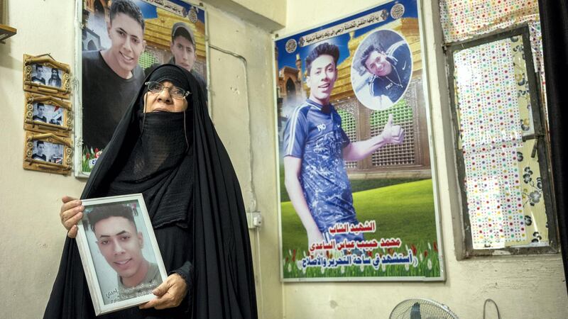 Layla Abbas Hussein, mother of two man slain during the protests in the living room of their small house, with pictures of her sons. Haider Husseini for The National