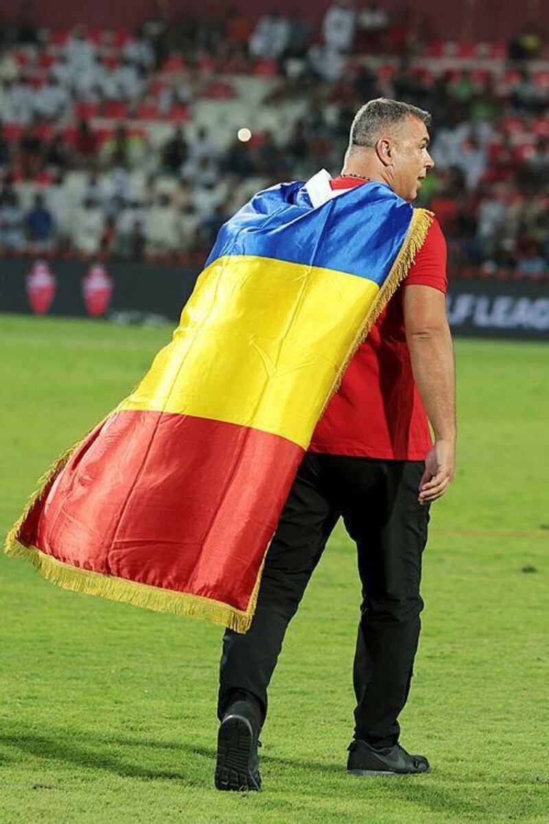 Al Ahli manager Cosmin Olaroiu celebrates draped in the flag of his native Romania after his team’s win in their final match of the season. Christopher Pike / The National