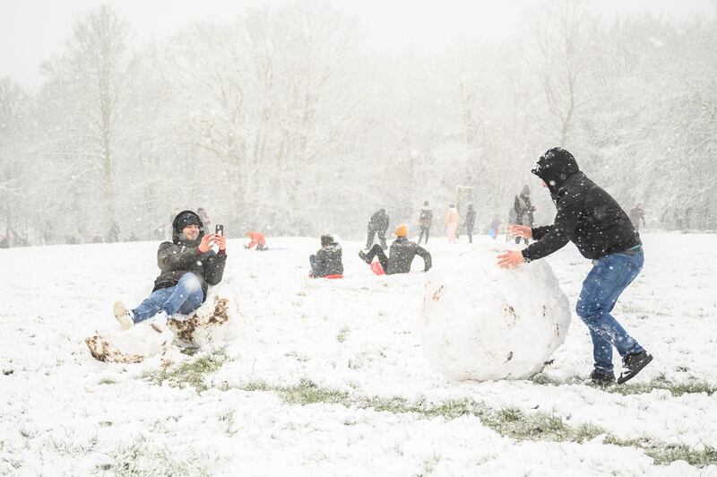 A man takes a photograph as his friend rolls a giant snowball at Alexandra Palace in London, United Kingdom. Parts of the country saw snow and icy conditions as arctic air caused temperatures to drop. Getty Images