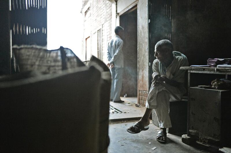 An Indian labourer sits and smokes bidis during a break at The New Sarkar Bidi Factory.