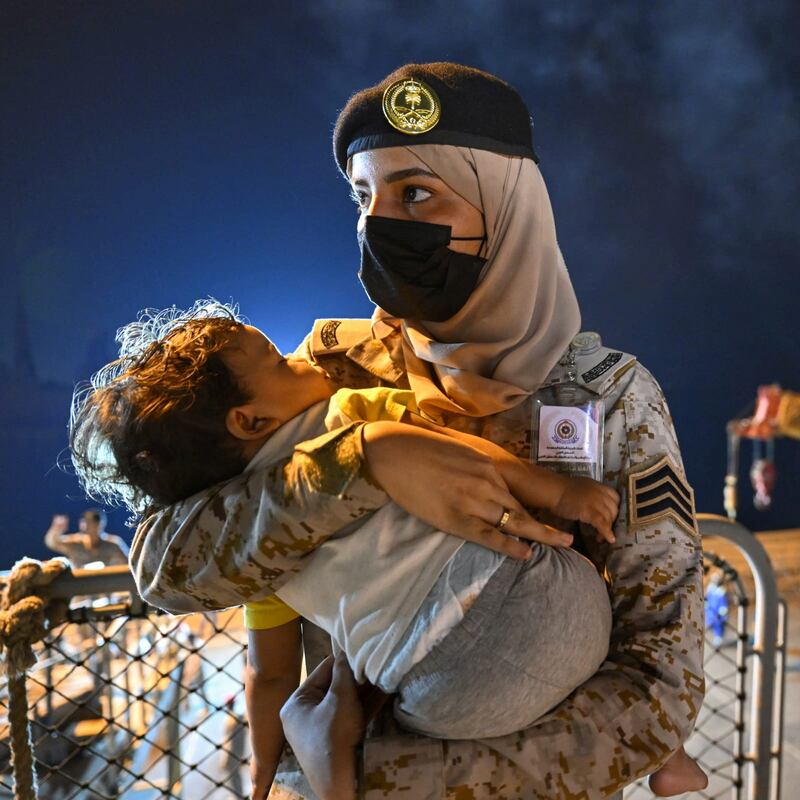 A member of the Saudi Royal Navy carries a child who was evacuated from Sudan, in Jeddah on April 24. Photo: SPA